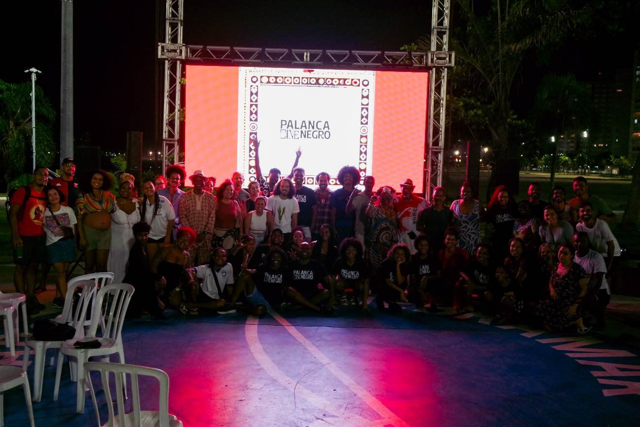 Foto coletiva do público e da equipe diante da tela no fim do festival
