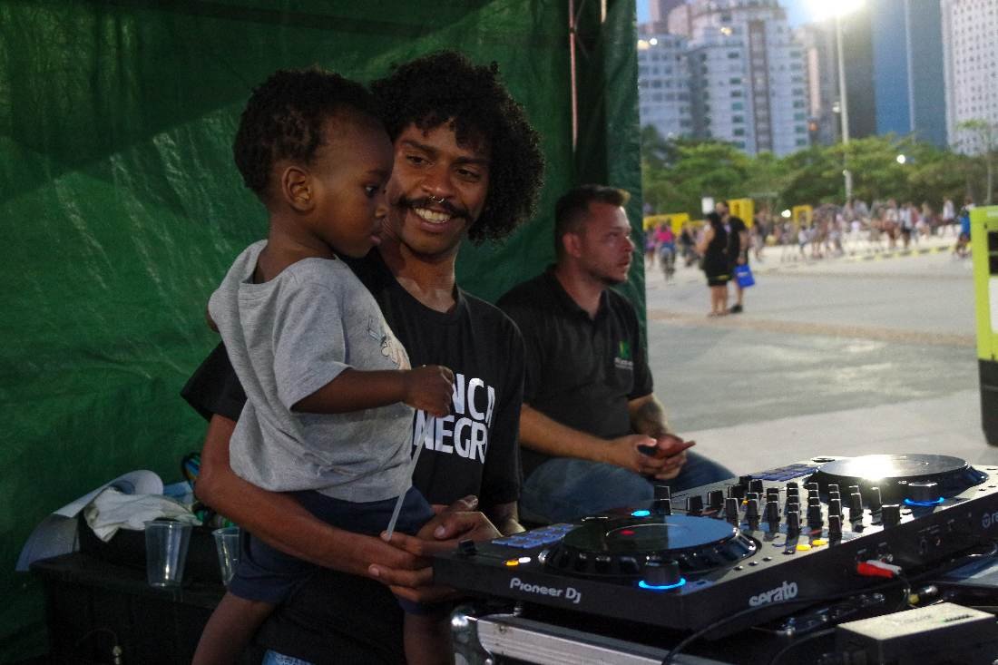 DJ com criança no colo comandando o som antes da sessão
